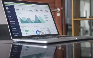 A laptop on a black table with analytics on screen