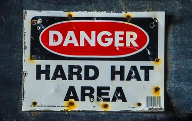 Old industrial warning sign that reads, Warning Hard hat area