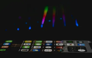 An iphone on the homescreen with lights in the background
